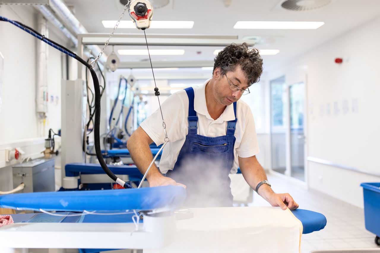 Ein Beschäftigter bearbeitet Bügelwäsche