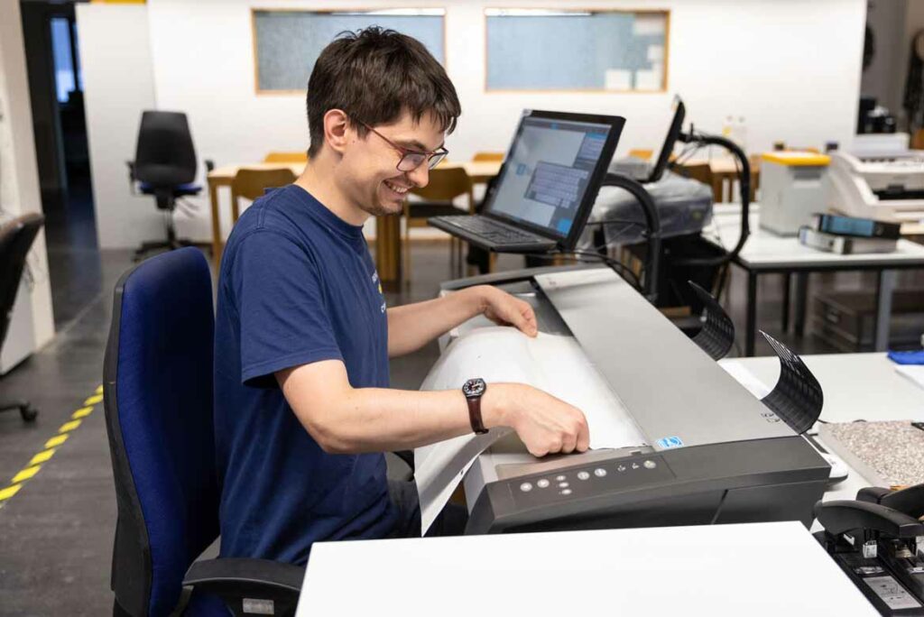 Ein Mitarbeiter digitalisiert einen Plan mit dem Großformatscanner