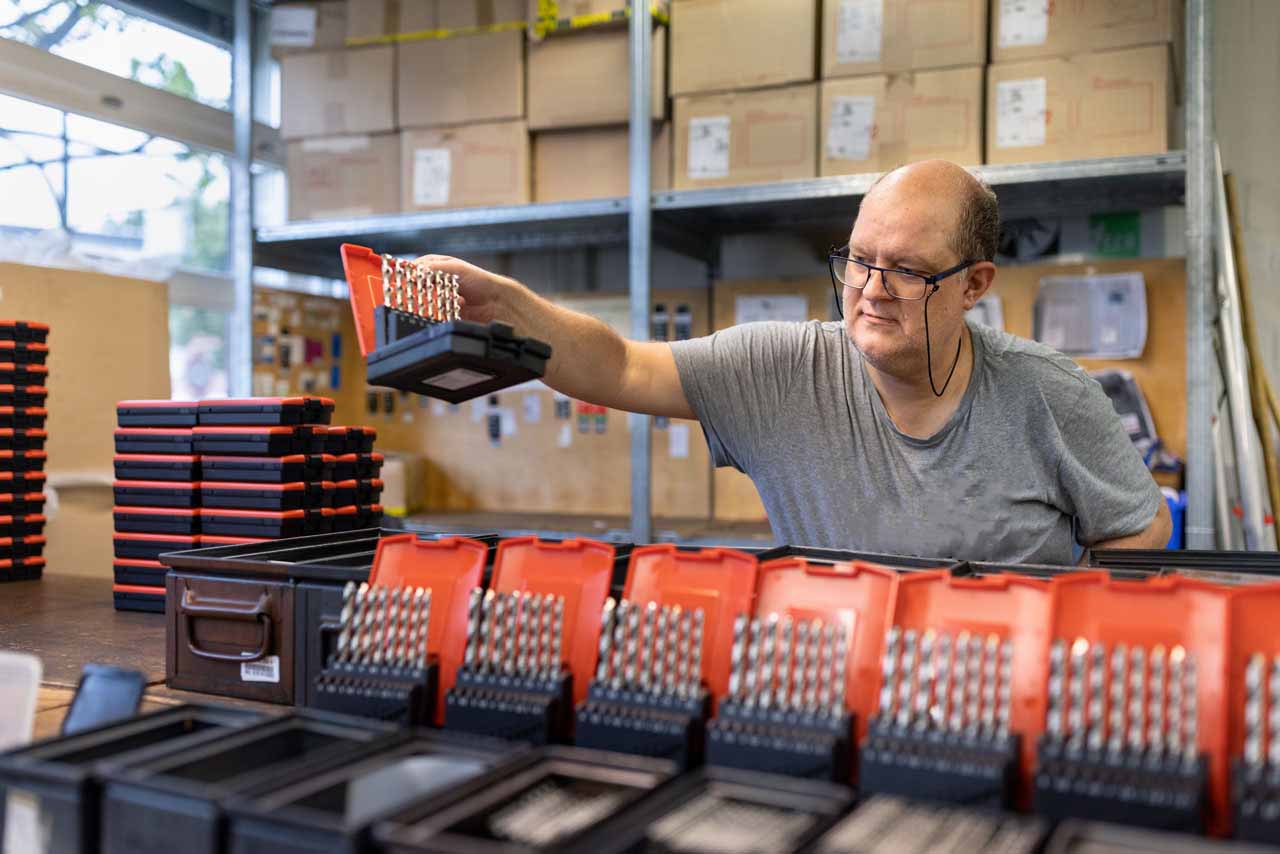 Ein Mitarbeiter der Lohnverpackung konfektioniert Bohrer in Aufbewahrungsboxen